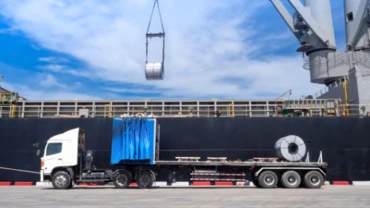 Steel coil being unloaded from a cargo ship onto a lorry