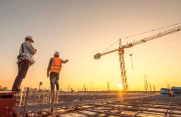 Workmen overlook building site in sunlight