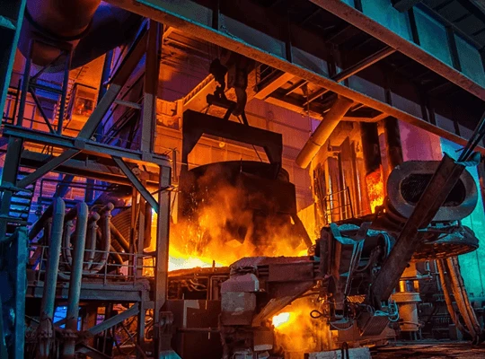 Molten steel being poured in a brightly lit steel manufacturing plant.