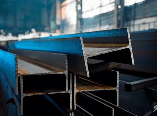 Close-up view of stacked steel beams in an industrial warehouse.
