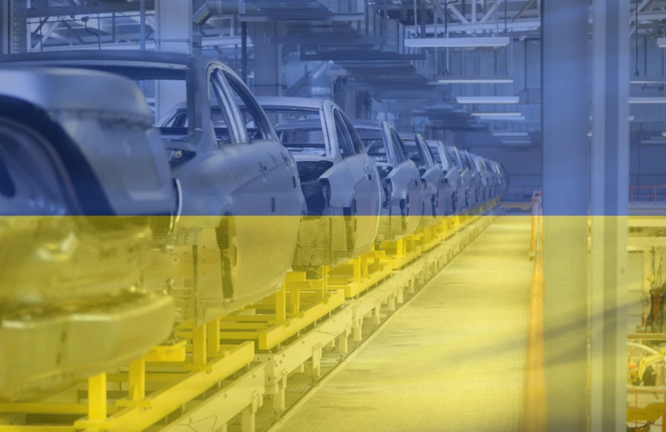 Assembling cars (Lada and Renault) at conveyor assembly line with ukraine flag at background